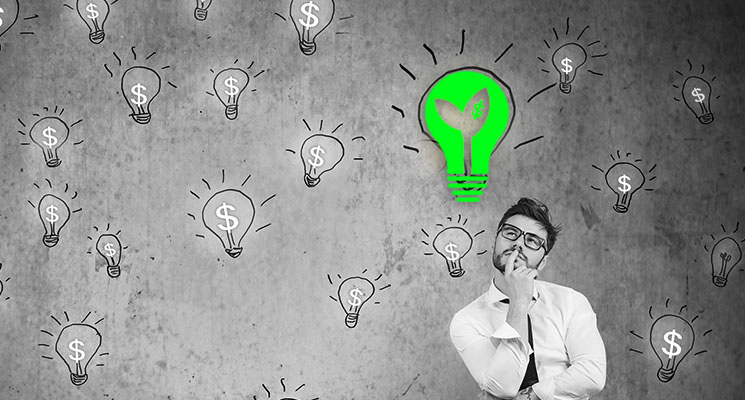 Portrait thinking handsome young man sitting on chair looking up at many dollar idea light bulbs above head